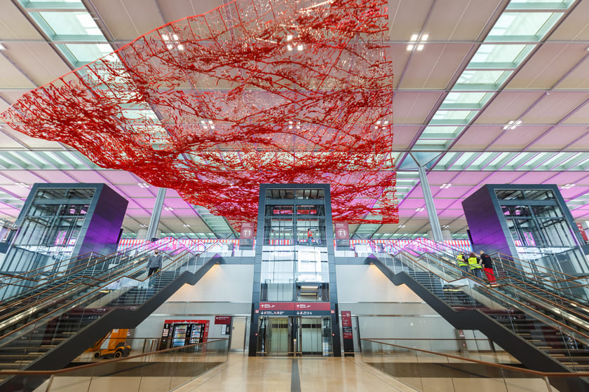 Interior moderno del Aeropuerto de Berlín Brandenburg (BER) con una gran instalación de arte rojo colgante.